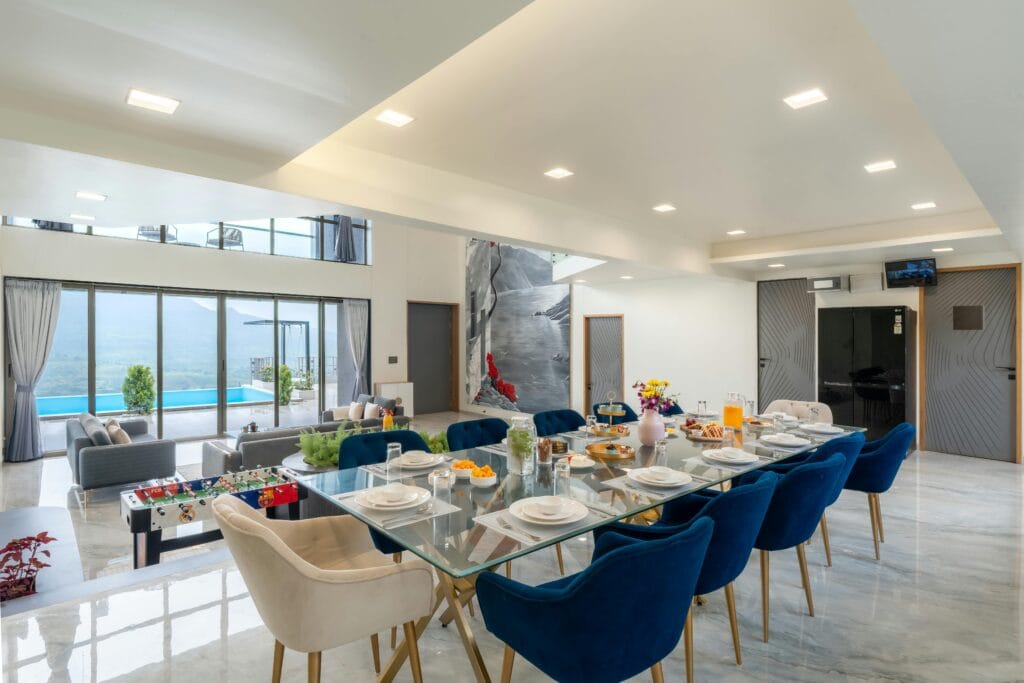 Spacious modern dining room with pool and mountain view, featuring elegant decor and seating.